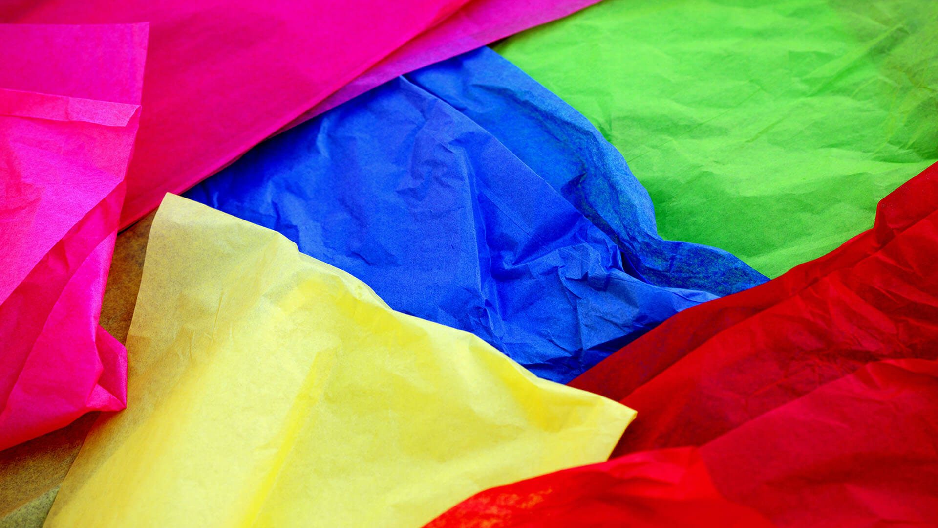 Crinkled sheets of bright pink, blue, green, red, and yellow tissue paper.