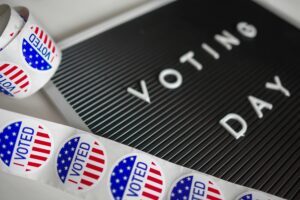 A black letter board spelling "VOTING DAY" with American flag "I VOTED" stickers surrounding it.