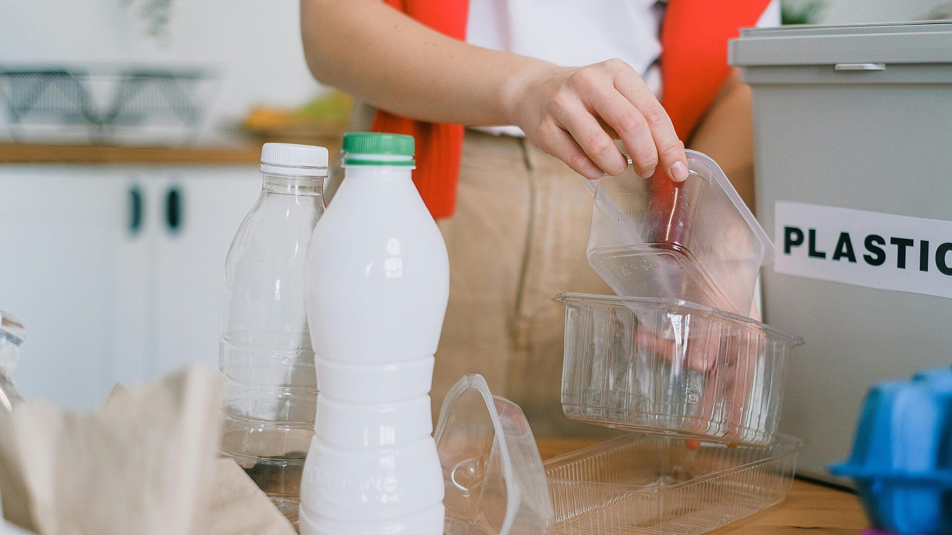 Woman recycling plastic containers and bottles at home.