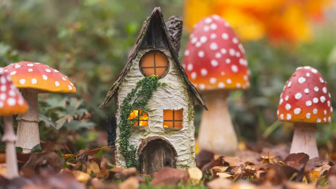 Charming tiny fairy house with glowing windows amidst red spotted mushrooms and autumn leaves.