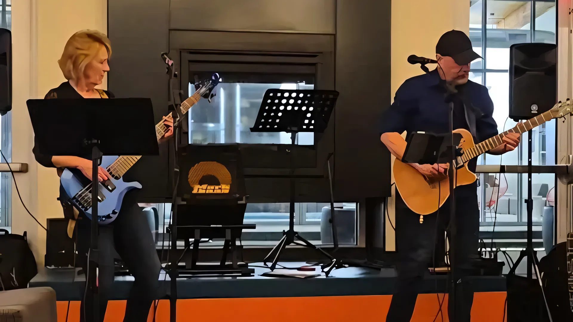 A live photo of the Victor Samalot Duo on stage, playing base guitar and acoustic guitar respectively.