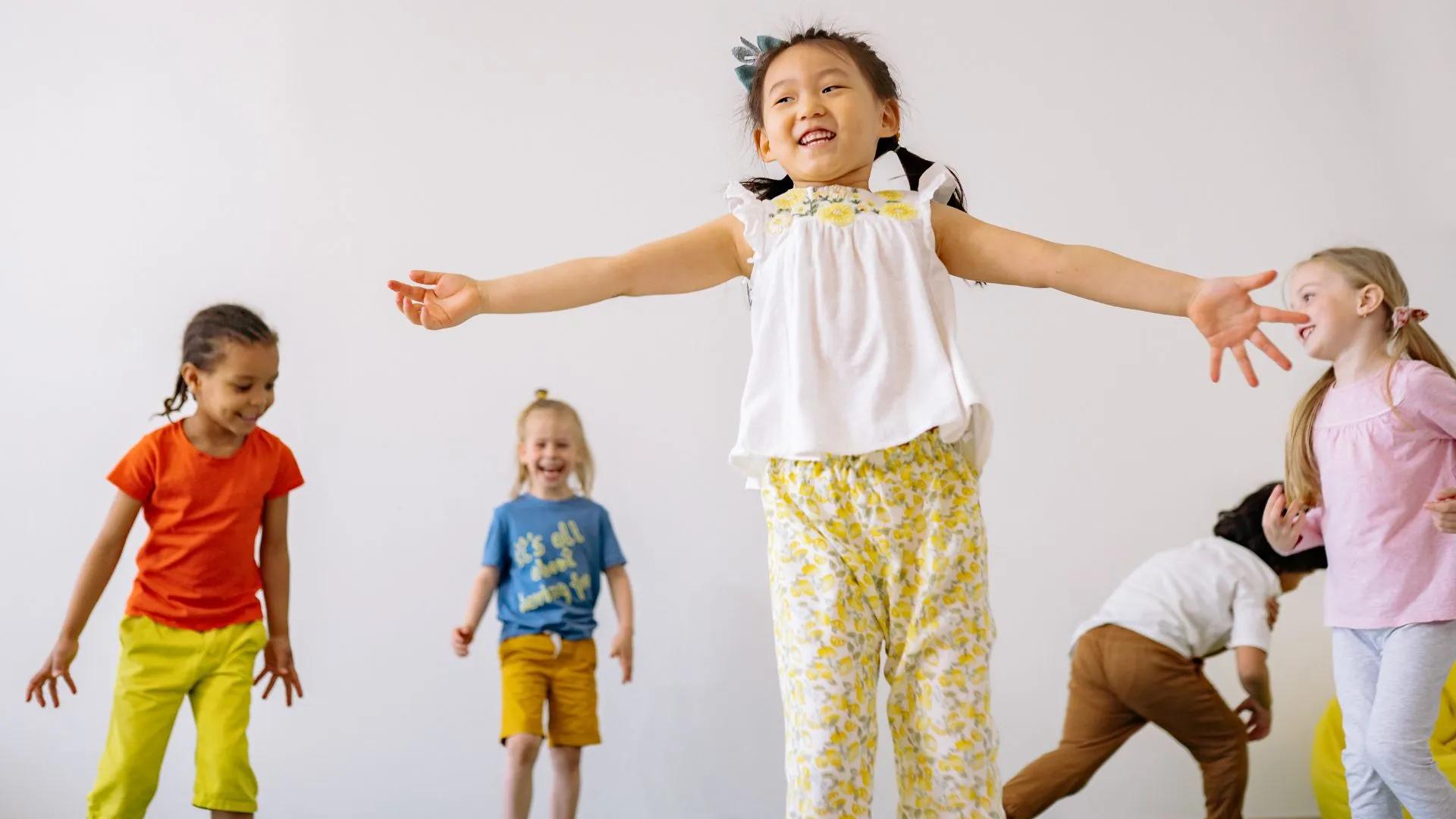 Joyful diverse children playing and jumping together against a white background.