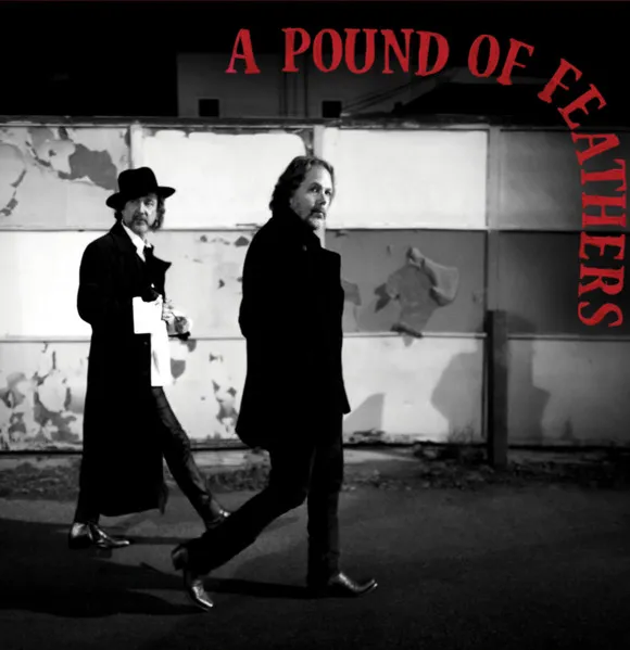Album cover: Two bearded men in long coats walk a dark street, B&W with red text 'A POUND OF FEATHERS'.